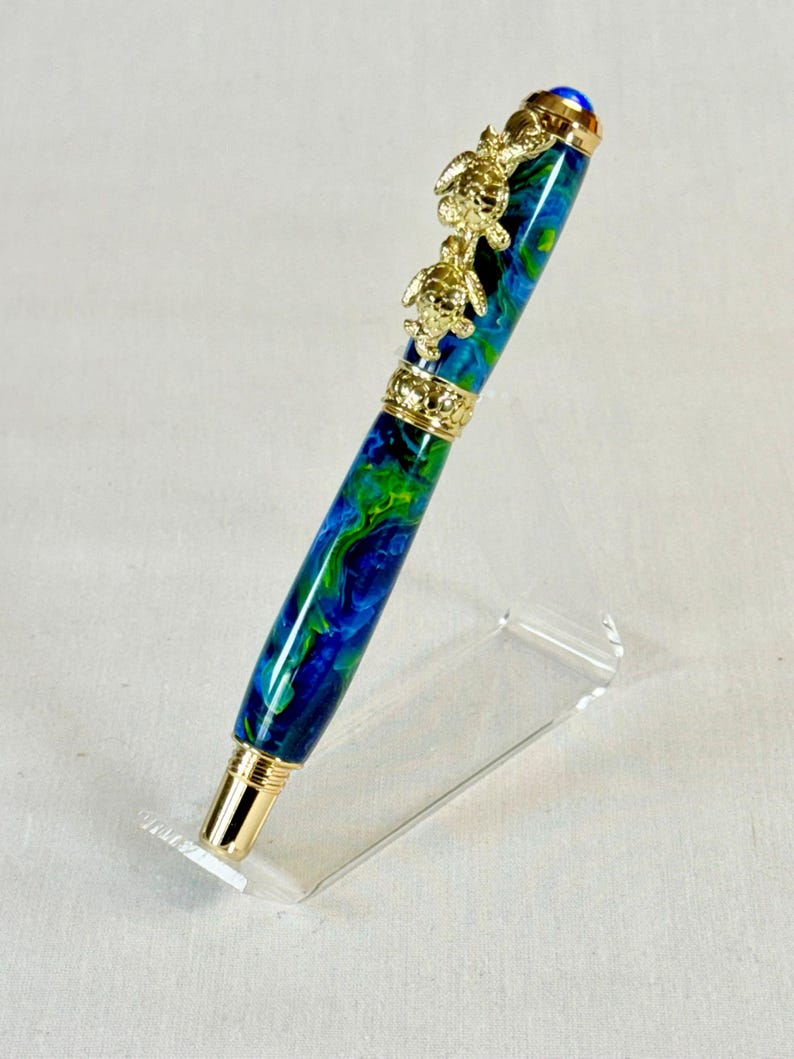The Sea Turtle Roller Ball pen features a stunning blue-ocean synthetic Fire Opal, turtle shell texture, and sea turtle clip. Truly a turtle lover gift. It comes either as a Rollerball or Fountain Pen. The cap posts securely with wide threads that won't cross. Hawaiian Honu Pen that has beautiful ocean themed features. One of my favorite Sea Creatures is the Sea Turtle. This Pen has it all. The pen comes with a windowed pen box making this item gift-ready.