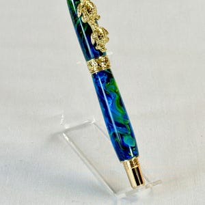 The Sea Turtle Roller Ball pen features a stunning blue-ocean synthetic Fire Opal, turtle shell texture, and sea turtle clip. Truly a turtle lover gift. It comes either as a Rollerball or Fountain Pen. The cap posts securely with wide threads that won't cross. Hawaiian Honu Pen that has beautiful ocean themed features. One of my favorite Sea Creatures is the Sea Turtle. This Pen has it all. The pen comes with a windowed pen box making this item gift-ready.