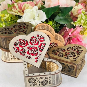 Peut inclure: Quatre boîtes en bois en forme de cœur avec des motifs de roses complexes. Les boîtes sont en bois brun clair avec un motif de roses rouges à l'intérieur. Les boîtes sont disposées en quinconce.