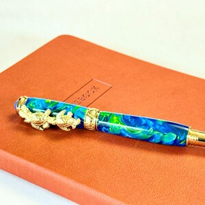 The Sea Turtle Roller Ball pen features a stunning blue-ocean synthetic Fire Opal, turtle shell texture, and sea turtle clip. Truly a turtle lover gift. It comes either as a Rollerball or Fountain Pen. The cap posts securely with wide threads that won't cross. Hawaiian Honu Pen that has beautiful ocean themed features. One of my favorite Sea Creatures is the Sea Turtle. This Pen has it all. The pen comes with a windowed pen box making this item gift-ready.
