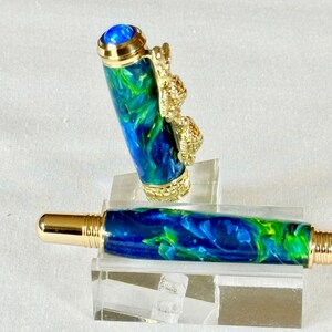 The Sea Turtle Roller Ball pen features a stunning blue-ocean synthetic Fire Opal, turtle shell texture, and sea turtle clip. Truly a turtle lover gift. It comes either as a Rollerball or Fountain Pen. The cap posts securely with wide threads that won't cross. Hawaiian Honu Pen that has beautiful ocean themed features. One of my favorite Sea Creatures is the Sea Turtle. This Pen has it all. The pen comes with a windowed pen box making this item gift-ready.