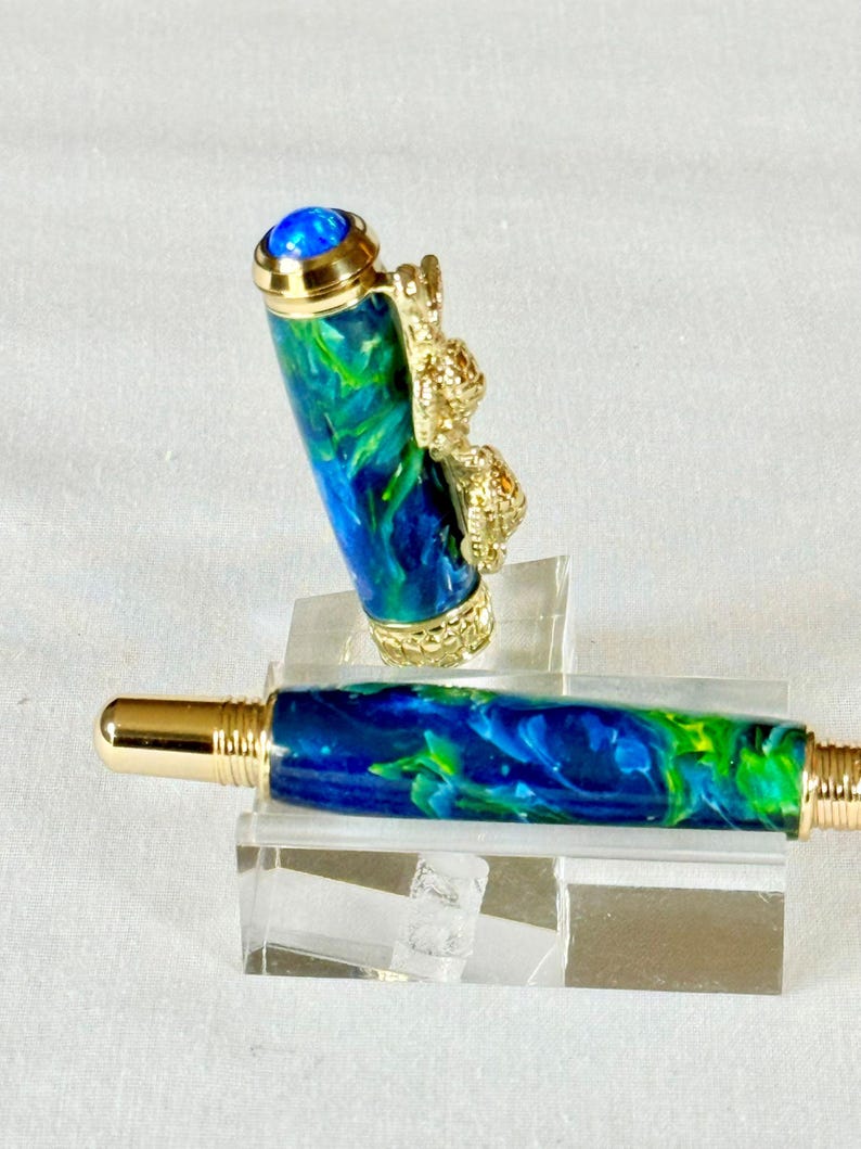 The Sea Turtle Roller Ball pen features a stunning blue-ocean synthetic Fire Opal, turtle shell texture, and sea turtle clip. Truly a turtle lover gift. It comes either as a Rollerball or Fountain Pen. The cap posts securely with wide threads that won't cross. Hawaiian Honu Pen that has beautiful ocean themed features. One of my favorite Sea Creatures is the Sea Turtle. This Pen has it all. The pen comes with a windowed pen box making this item gift-ready.