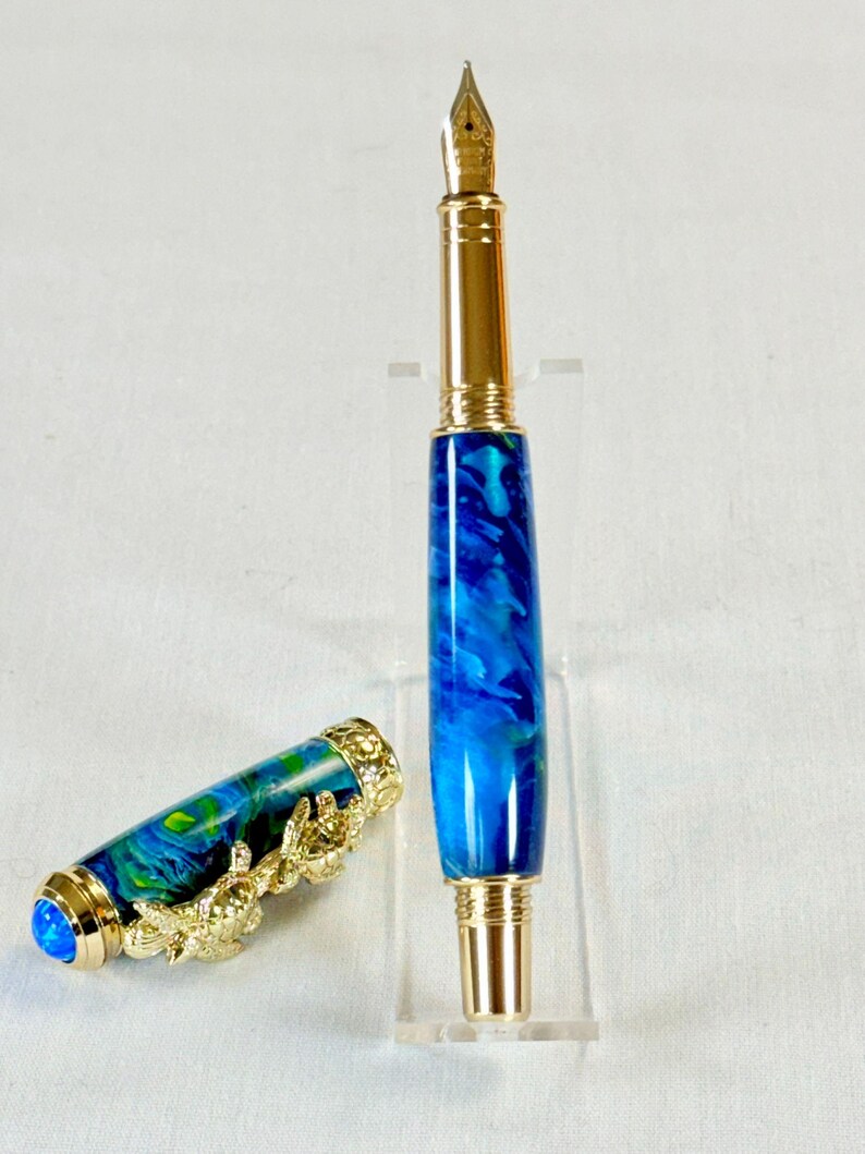 The Sea Turtle Roller Ball pen features a stunning blue-ocean synthetic Fire Opal, turtle shell texture, and sea turtle clip. Truly a turtle lover gift. It comes either as a Rollerball or Fountain Pen. The cap posts securely with wide threads that won't cross. Hawaiian Honu Pen that has beautiful ocean themed features. One of my favorite Sea Creatures is the Sea Turtle. This Pen has it all. The pen comes with a windowed pen box making this item gift-ready.
