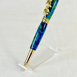 The Sea Turtle Roller Ball pen features a stunning blue-ocean synthetic Fire Opal, turtle shell texture, and sea turtle clip. Truly a turtle lover gift. It comes either as a Rollerball or Fountain Pen. The cap posts securely with wide threads that won't cross. Hawaiian Honu Pen that has beautiful ocean themed features. One of my favorite Sea Creatures is the Sea Turtle. This Pen has it all. The pen comes with a windowed pen box making this item gift-ready.