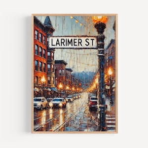 May include: An oil painting of Larimer Street at night, framed in a light wood. The street sign is visible. Buildings with orange and brown facades line the street, illuminated by streetlights and car headlights. The sky is a mix of blue and grey.
