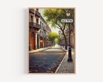 May include: A framed print of a European street scene. The artwork depicts a cobblestone street lined with buildings and trees. A street sign reads "CALLE MITRE". The artwork is in a wooden frame.