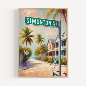Puede incluir: Impresión artística enmarcada de una escena callejera con un letrero verde "Simonton St". La obra representa una calle tropical con palmeras, casas coloridas y una bicicleta. El estilo es impresionista con pinceladas visibles.