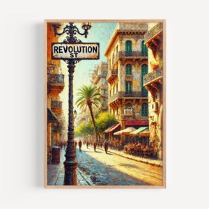 May include: A framed art print showing a street scene with a sign reading "REVOLUTION ST." The artwork depicts a European street with buildings, people, and a palm tree. The colour palette is warm, with yellows, browns, and greens.