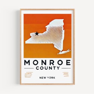 May include: A white outline of the state of New York with a black star marking the location of Monroe County, New York. The background is a gradient of orange and yellow. The text "MONROE COUNTY NEW YORK" is printed below the map.