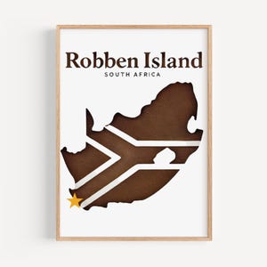 Puede incluir: Una impresión enmarcada que presenta un mapa de Sudáfrica con un diseño recortado. El texto "Robben Island SOUTH AFRICA" se muestra en marrón. La bandera sudafricana es visible dentro del mapa, con una estrella amarilla.