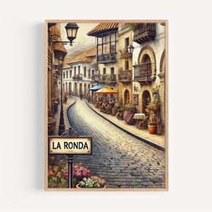 May include: A framed watercolour print depicting a street scene in La Ronda, with buildings and balconies. A street sign reads "LA RONDA". The artwork has a warm colour palette, focusing on architectural details and street life, with cobblestones.
