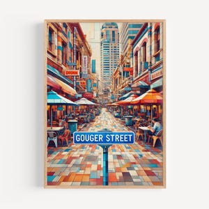 Puede incluir: Una impresión artística enmarcada que representa Gouger Street, una escena urbana vibrante con restaurantes y tiendas. La obra de arte presenta edificios coloridos, toldos y una señal de calle azul. La imagen es una ilustración digital con una paleta de colores cálidos.