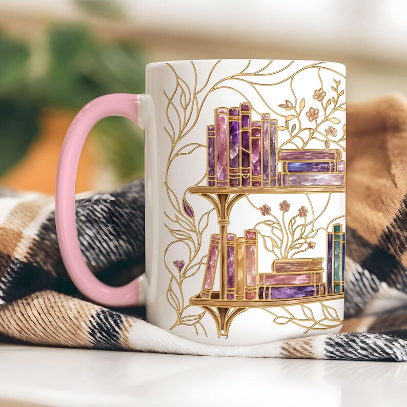 Pode incluir: Uma caneca de cer&acirc;mica branca com uma asa rosa pastel, apresentando uma ilustra&ccedil;&atilde;o de linhas douradas de duas prateleiras cheias de livros com aspeto de cristal em tons de roxo, rosa e azul, com delicadas vinhas douradas.