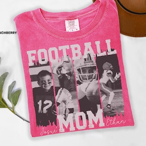 May include: A pink Comfort Colors t-shirt with a distressed graphic. The graphic reads "FOOTBALL MOM" in white block letters, with black and white photos of football players. The names "Josue" and "Ethan" are written in script.