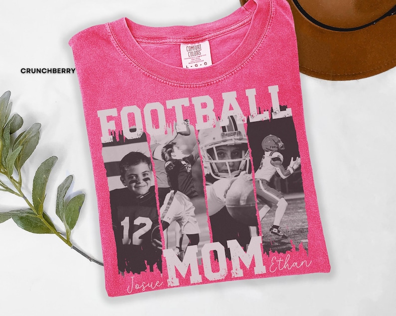 May include: A pink Comfort Colors t-shirt with a distressed graphic. The graphic reads "FOOTBALL MOM" in white block letters, with black and white photos of football players. The names "Josue" and "Ethan" are written in script.