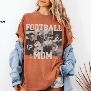 May include: A burnt orange t-shirt with the words "FOOTBALL MOM" in white block letters. The shirt features four black and white images of football players. The names "Jessee" and "Ethan" are printed below the word "MOM".
