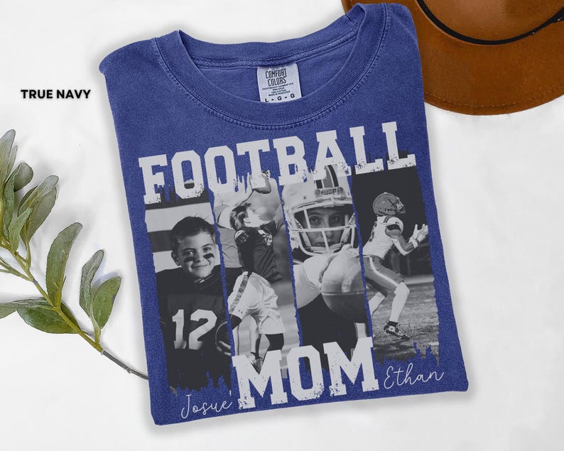 May include: A navy blue t-shirt with the words "FOOTBALL MOM" in white block letters. The shirt features a collage of black and white photos of football players. The name "Ethan" is written in script below the word "MOM". The word "TRUE NAVY" is printed on the top left.