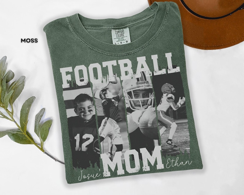 May include: Moss green t-shirt with a football-themed design. The shirt features the words "FOOTBALL MOM" in large white letters, along with black and white photos of football players. The name "Ethan" is written in script.