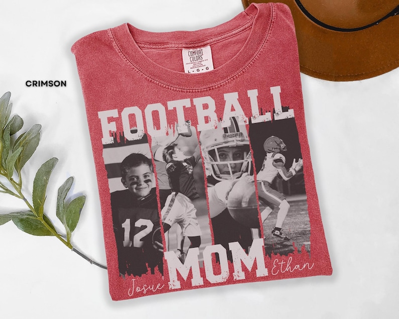 May include: Crimson red t-shirt with the words "FOOTBALL MOM" in white block letters. The shirt features a collage of black and white photos of football players. The names "Josue" and "Ethan" are written in script.