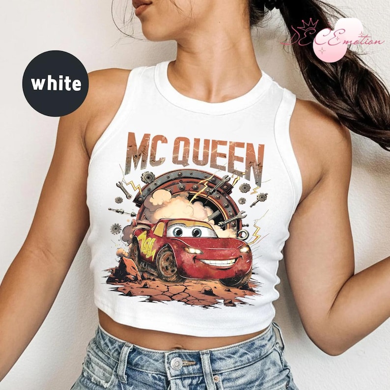 May include: White crop top featuring a graphic of Lightning McQueen from the film Cars. The design includes the text "MC QUEEN" above the car, set against a backdrop of tools and a circular frame.