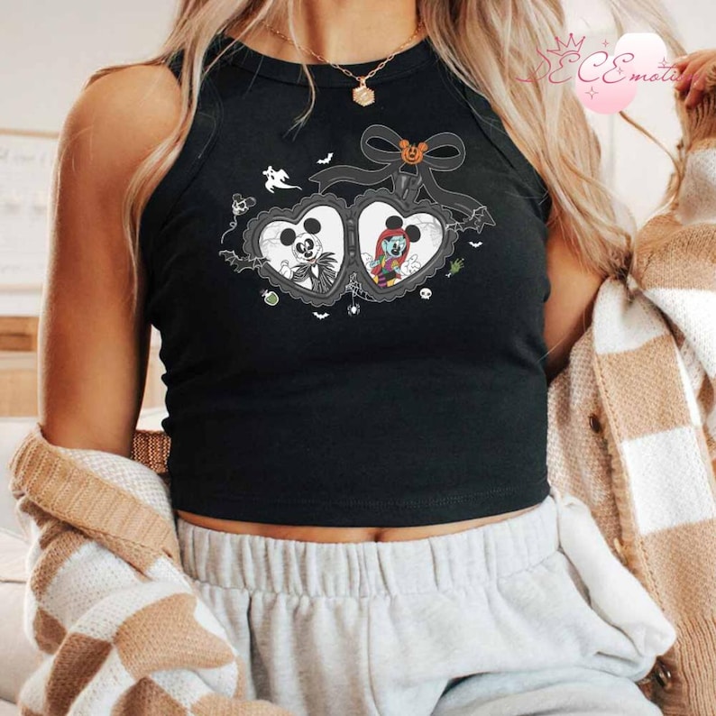 Puede incluir: Camiseta sin mangas negra con un dise&ntilde;o en forma de coraz&oacute;n con Jack Skellington y Sally de Pesadilla antes de Navidad. El dise&ntilde;o incluye murci&eacute;lagos, fantasmas y un lazo con una calabaza. La camiseta sin mangas es sin mangas.