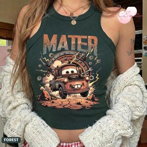 May include: Forest green tank top with a graphic of Mater from the film Cars. The design features the word "MATER" in orange and grey, with a cartoon image of Mater surrounded by tools and lightning bolts.