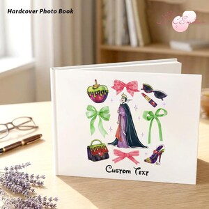 May include: White hardcover photo book with a colorful illustration of a poison apple, bows, sunglasses, lipstick, a purse, a high-heeled shoe, and a queen. The text "Hardcover Photo Book" and "Custom Text" are visible.