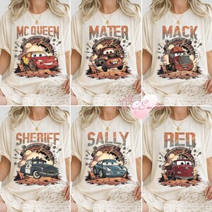 May include: Cream-coloured t-shirts featuring characters from the film Cars. Each shirt displays a different character's name in a distressed font above a graphic of the character. Characters include McQueen, Mater, Mack, Sheriff, Sally, and Red.