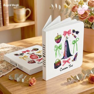 May include: White board book with colorful illustrations of bows, a purse, a poison apple, and a queen. The text "Custom Text" is printed on the cover and spine. Another book is lying flat on a wooden table.