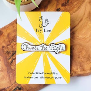 Könnte beinhalten: Eine silberne Emaille-Anstecknadel mit weißem Hintergrund und schwarzem Text, der "Choose the Right" lautet. Die Anstecknadel befindet sich auf einem gelben und weißen Hintergrund mit einem Sonnenstrahlenmuster. Der Hintergrund enthält auch den Text "Ivy Lee" und "Collectible Enamel Pins".