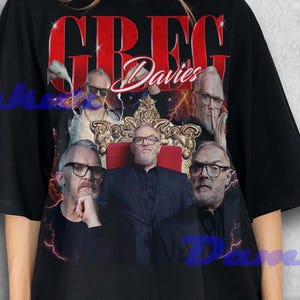 May include: Black t-shirt featuring a graphic of Greg Davies in various poses, with the name "Greg Davies" in red block letters. The design includes a regal chair and a crown. The shirt is worn by a person.
