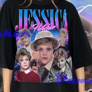 Puede incluir: Camiseta negra con un gráfico retro de Jessica Fletcher, con el texto "JESSICA Fletcher". El diseño incorpora múltiples imágenes del personaje. El fondo tiene un efecto de relámpagos morados y azules.
