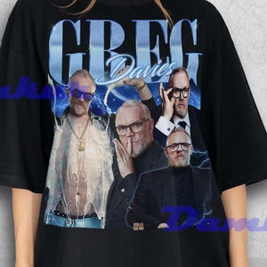 May include: Black t-shirt with a graphic of Greg Davies, featuring his name in a blue, stylized font. The design has a vintage, faded appearance. The shirt is worn by a person.