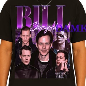 May include: Black t-shirt featuring a purple graphic with the name "Bill Skarsgard" and multiple images of the actor. The design includes a purple lightning bolt effect. The shirt is worn by a person wearing sunglasses.