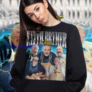 May include: Black sweatshirt featuring a graphic of Keith Brymer Jones and the text "Keith Brymer Jones". The graphic includes multiple images of the person. The background has a blue and white lightning design.