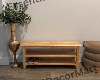 May include: A light wood shoe rack with two shelves. The rack is sitting on a brown tiled floor. There are two pairs of shoes on the bottom shelf. The rack is labeled "EssentialDecorMart".