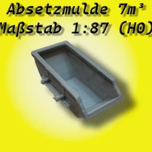 Könnte beinhalten: Ein graues Plastikmodell einer 7 Kubikmeter Kippmulde, beschriftet "Absetzmulde 7m³ Maßstab 1:87 (HO)".