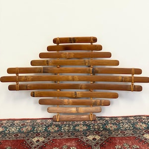 May include: A wall hanging made of woven bamboo strips in a geometric pattern. The bamboo is a natural brown color and the strips are tied together with twine.