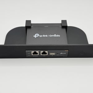 Könnte beinhalten: Schwarzer Netzwerkrouter mit einem weißen tp-link | Omada-Logo. Der Router verfügt über zwei Ethernet-Ports, einen USB-Port und einen Stromanschluss.