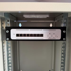 Könnte beinhalten: Ein Netzwerk-Switch, montiert in einem beigefarbenen Serverschrank. Der Switch hat mehrere Anschlüsse und Kontrollleuchten. Das Rack ist mit "DIGITUS" beschriftet und hat Montageschienen.