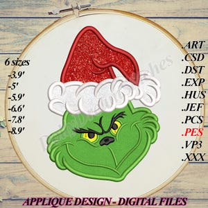 Peut inclure: Un motif de broderie représentant un personnage vert aux yeux jaunes portant un bonnet de Père Noël rouge pailleté avec une bordure blanche. Le motif est présenté dans un tambour en bois avec du texte indiquant 6 tailles de 9,9 à 22,6 cm et des formats de fichiers incluant ART, CSD, DST, EXP, HUS, JEF, PCS, PES, VP3 et XXX.