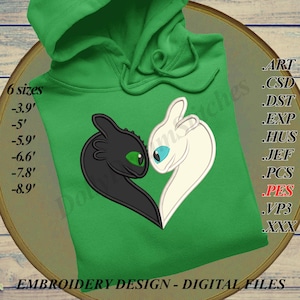 Può includere: Una felpa con cappuccio verde con un ricamo di due draghi stilizzati, uno nero con un occhio verde e l'altro bianco con un occhio blu. Il design è etichettato "EMBROIDERY DESIGN - DIGITAL FILES" e include opzioni di dimensioni da 119 cm a 271 cm.