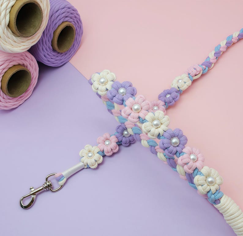 May include: A braided macrame lanyard featuring pastel pink, lavender, and light blue cord woven into flower shapes with white faux pearl centers. A silver-toned metal swivel lobster clasp is attached to one end of the floral cord strap.