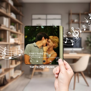 May include: A digital music player with a photo of a couple on the screen. The song "Until I found you" by Stephen Sanchez is playing. The screen shows the song title, artist name, and playback controls. The text "TAP TO PLAY MUSIC" is displayed below the screen.