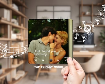 May include: A digital music player with a photo of a couple on the screen. The song "Until I found you" by Stephen Sanchez is playing. The screen shows the song title, artist name, and playback controls. The text "TAP TO PLAY MUSIC" is displayed below the screen.
