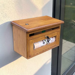 May include: A white ceramic mug with a black handle and the text "But First, Coffee" in a black, handwritten-style font. The mug is on a white surface.