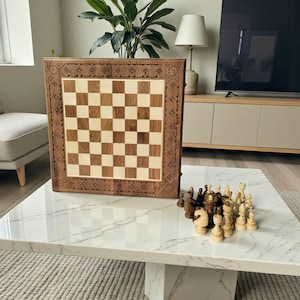 Könnte beinhalten: Ein Schachspiel aus Holz mit dekorativem Rand. Das Schachbrett hat abwechselnd helle und dunkle Quadrate. Schachfiguren sind auf einem weißen Marmor-Couchtisch angeordnet. Das Set enthält helle und dunkle Schachfiguren.