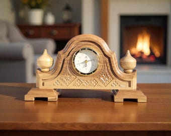 Puede incluir: Un reloj de repisa de madera con acabado marrón claro. El reloj tiene una esfera redonda con borde dorado y números romanos negros. El reloj está intrincadamente tallado con patrones florales y geométricos. Dos pináculos decorativos se encuentran a cada lado de la esfera.