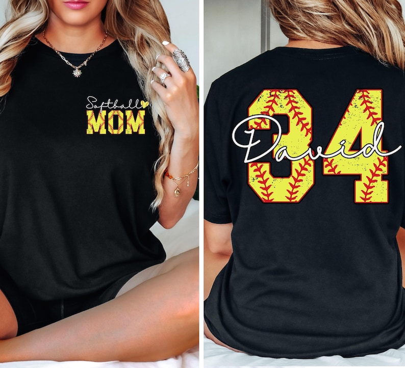 Puede incluir: Camiseta negra con "Softball MOM" en texto amarillo y negro en la parte delantera. La parte trasera de la camiseta presenta un dise&ntilde;o con tem&aacute;tica de b&eacute;isbol con el n&uacute;mero "34" y el nombre "David" en letra cursiva.