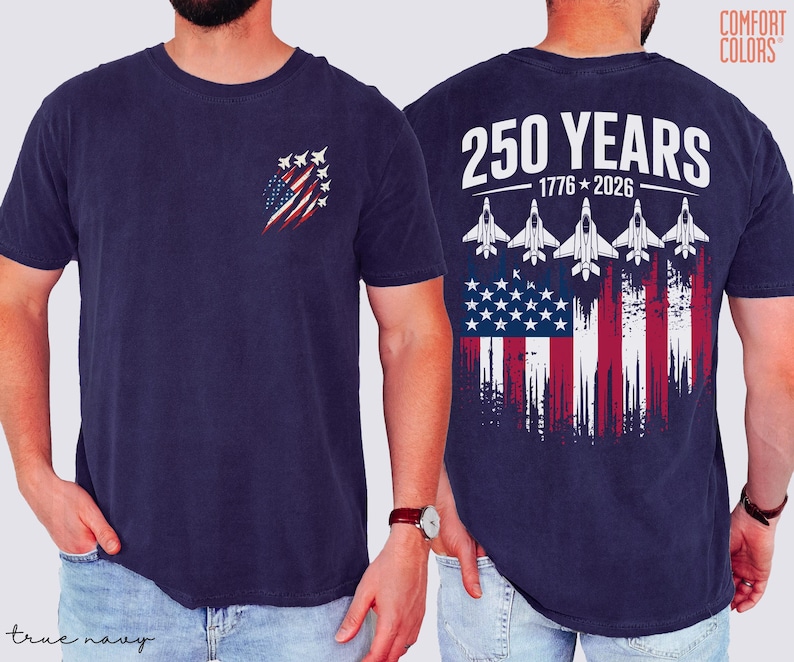 May include: A navy blue t-shirt featuring a small graphic on the left chest of a distressed American flag with fighter jets. The back displays the text 250 YEARS 1776-2026 above five fighter jets flying over a large distressed American flag.